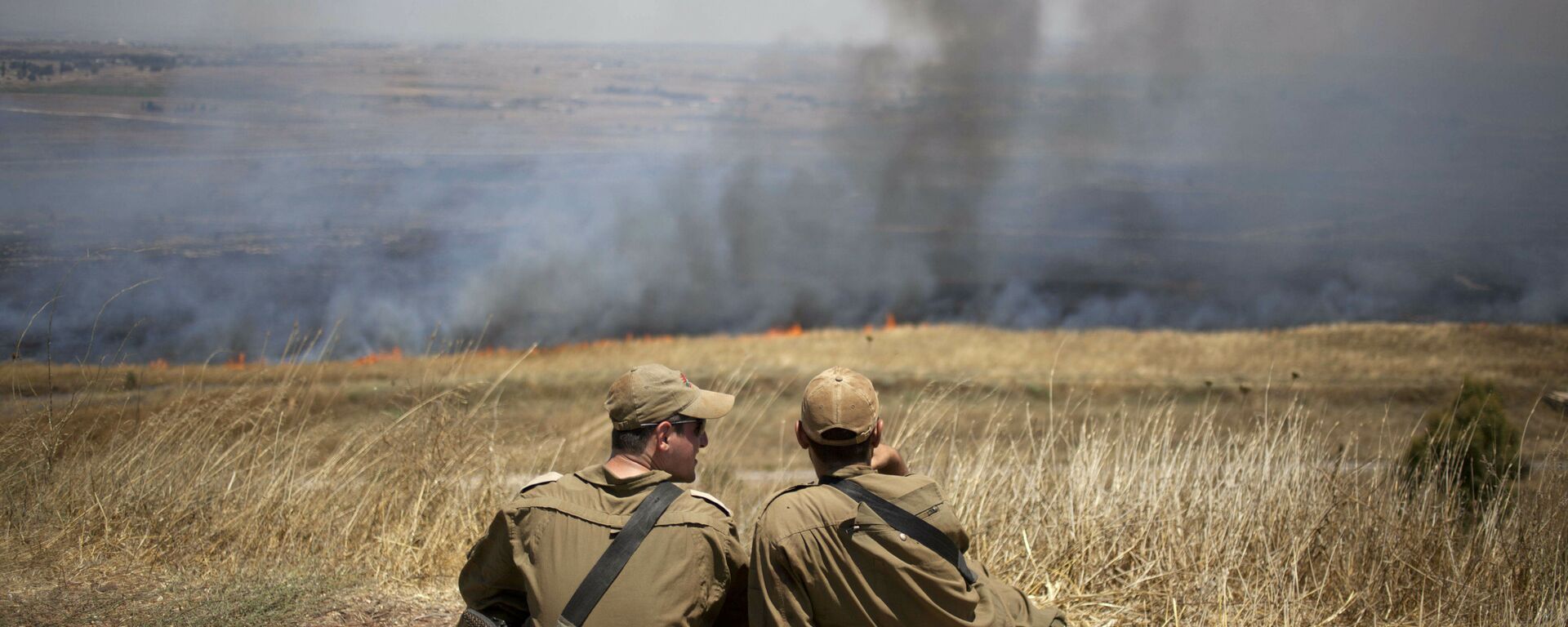 FILE - In this July 16, 2013, file photo, Israeli soldiers sit in a position on the border with Syria on the Israeli-controlled Golan Heights as smoke rises following explosions of mortar shells - Sputnik International, 1920, 11.10.2021