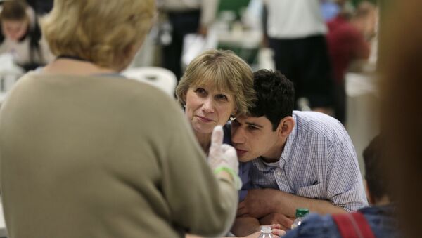 In this August 13, 2014 photograph, Andrew Goldberg rests his head on the shoulder of his mother Louisa as they listen to a therapist in the school cafeteria at the Judge Rotenberg Educational Center in Canton, Massachusetts.  Andrew, who was born with a developmental disorder, wears a electrical shocking device to control violent episodes.  - Sputnik International