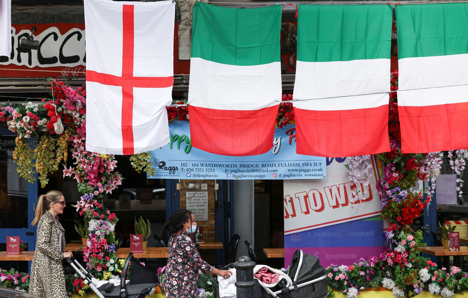 People walk past a restaurant displaying Italy and England flags, in London, Britain, July 9, 2021.  - Sputnik International, 1920, 07.09.2021