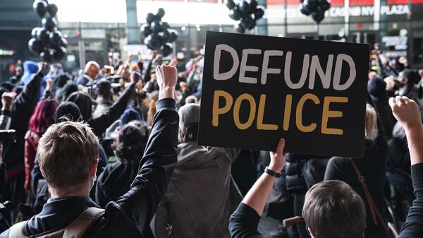 In this 14 October 2020 file photo, a protester holds a sign that reads Defund Police during a rally for the late George Floyd outside Barclays Center in New York - Sputnik International