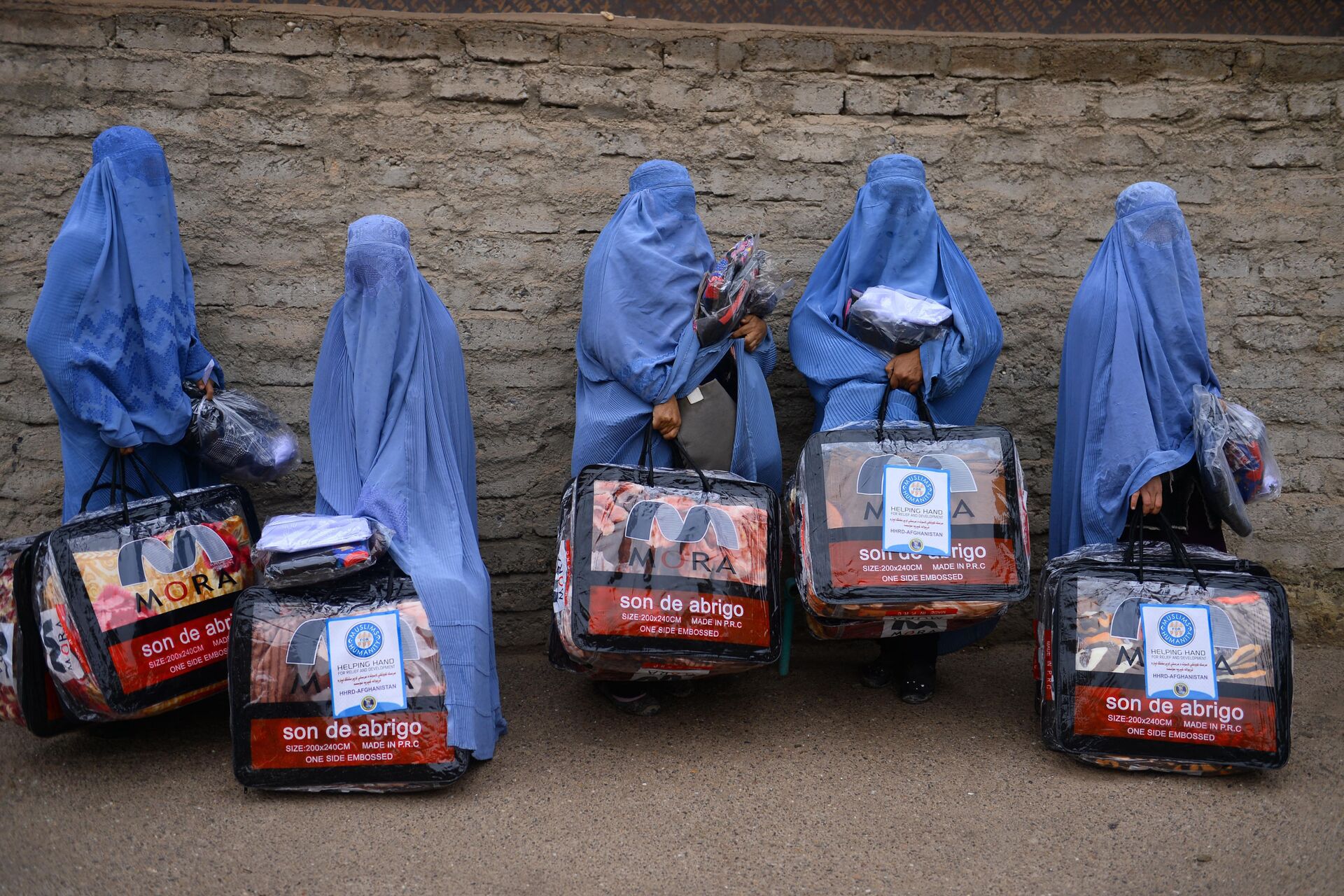 In this photograph taken on December 19, 2019, Afghan burqa-clad women stand with aid items recieved from a charity in Herat. - Sputnik International, 1920, 10.09.2021