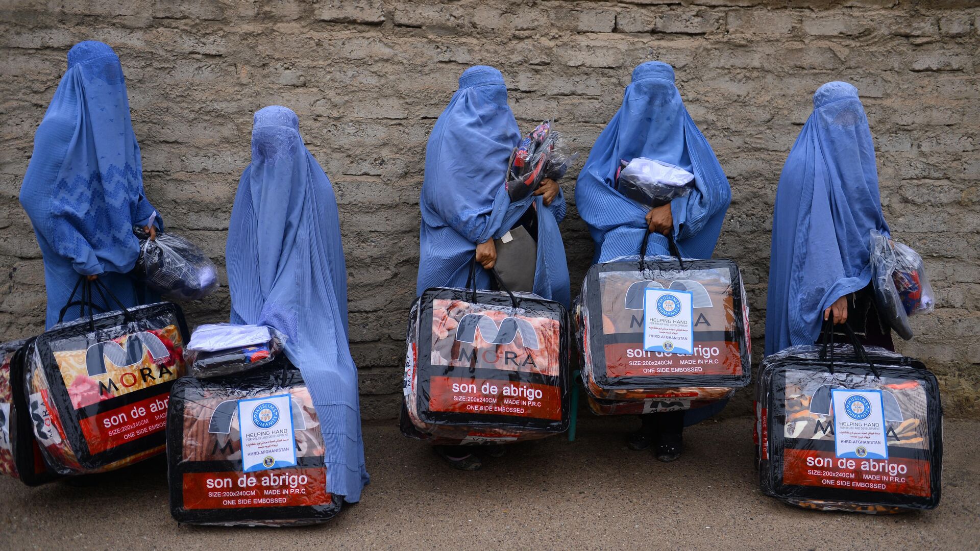 In this photograph taken on December 19, 2019, Afghan burqa-clad women stand with aid items recieved from a charity in Herat. - Sputnik International, 1920, 05.09.2021