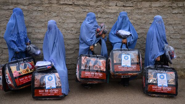 In this photograph taken on December 19, 2019, Afghan burqa-clad women stand with aid items recieved from a charity in Herat. - Sputnik International