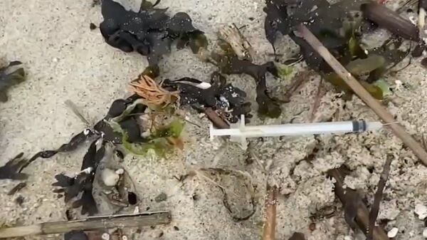 Screenshot captures one of dozens of syringes that have washed ashore along the New Jersey coastline after intense storms have overflowed the local sewer systems. - Sputnik International