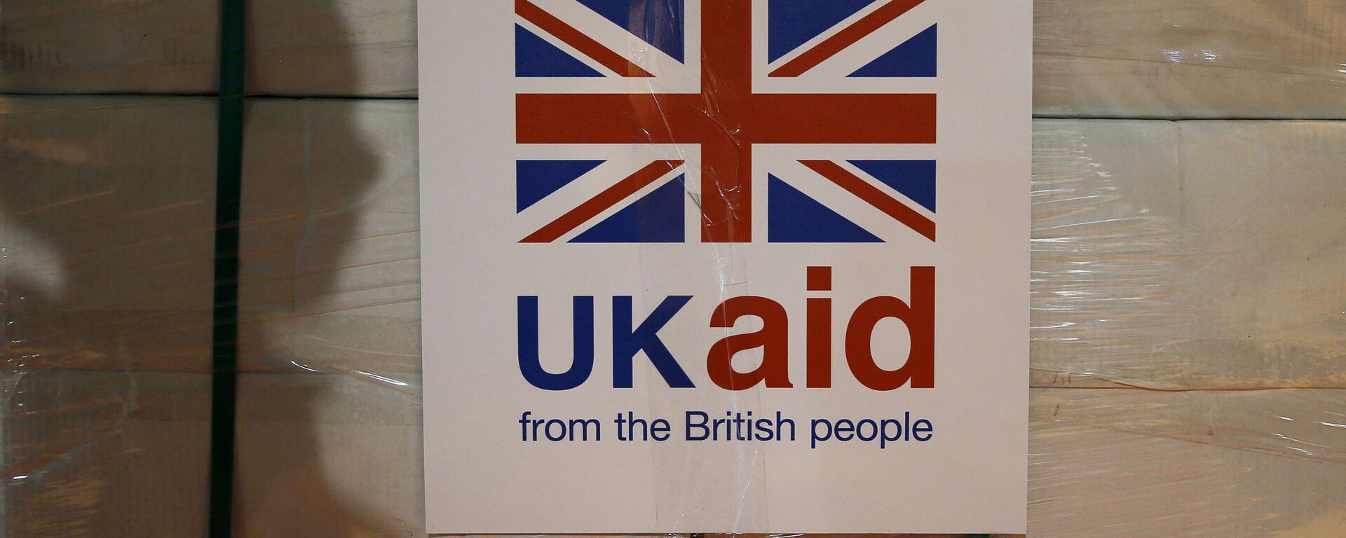A UK aid label is attatched to a box containing kitchen sets, stored at a UK Aid Disaster Response Centre where humanitarian supplies are being collected to be airlifted to Iraq at Cotswold Airport near the village of Kemble, Gloucestershire, southern England on August 14, 2014 - Sputnik International, 1920, 13.07.2021