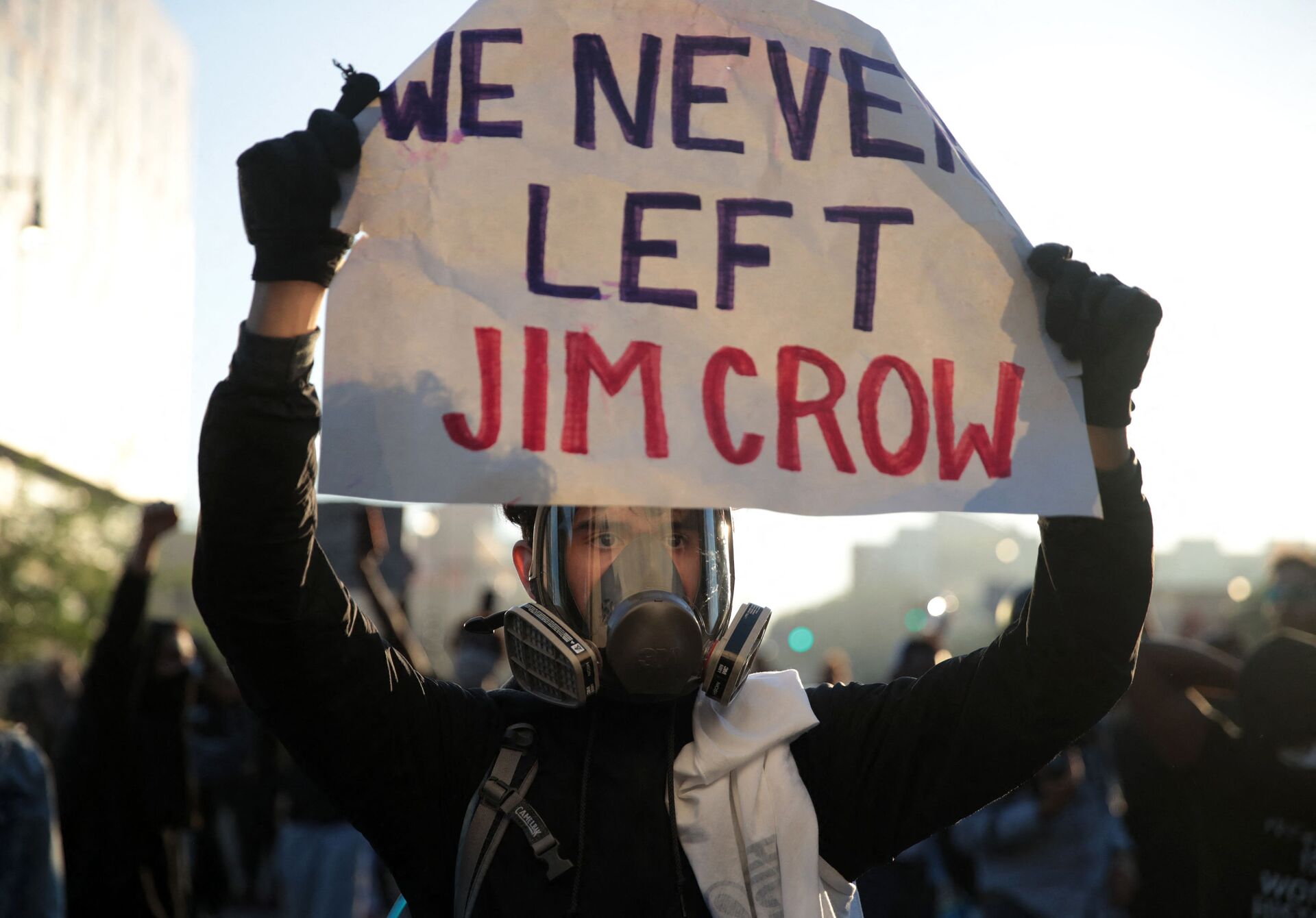A protester holds up a sign that reads We Never Left Jim Crow during a protest sparked by the death of George Floyd while in police custody on May 29, 2020 in Minneapolis, Minnesota. Earlier today, former Minneapolis police officer Derek Chauvin was taken into custody for Floyd's death. Chauvin has been accused of kneeling on Floyd's neck as he pleaded with him about not being able to breathe. Floyd was pronounced dead a short while later. Chauvin and 3 other officers, who were involved in the arrest, were fired from the police department after a video of the arrest was circulated. - Sputnik International, 1920, 07.09.2021