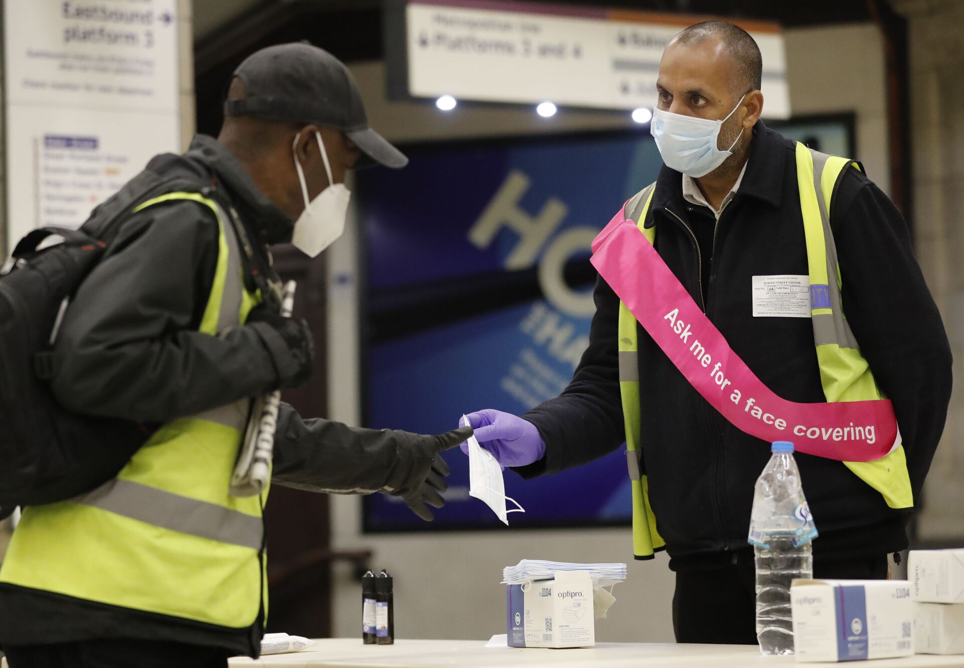 A London Underground worker, right, hands over a free face masks to a passenger at London's Baker Street station, Tuesday, June 9, 2020. Wearing a face mask will become compulsory on the London TFL public transport service starting from June 15, 2020, as a safety measure to contrast the COVID-19 pandemic.  - Sputnik International, 1920, 24.10.2021