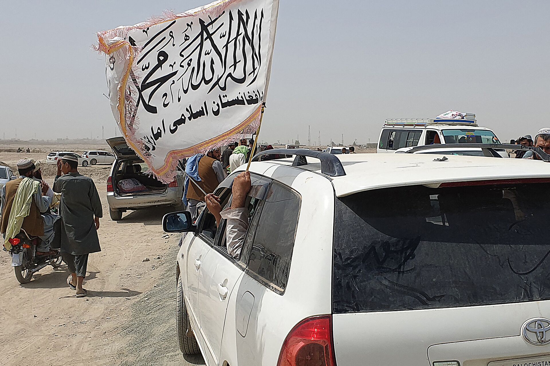 People wave a Taliban flag as they drive through the Pakistani border town of Chaman on July 14, 2021, after the Taliban claimed they had captured the Afghan side of the border crossing of Spin Boldak along the frontier with Pakistan - Sputnik International, 1920, 07.09.2021