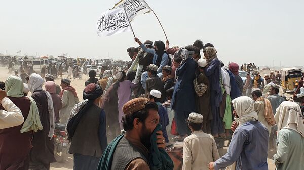 People wave Taliban flags as they drive through the Pakistani border town of Chaman on July 14, 2021, after the Taliban claimed they had captured the Afghan side of the border crossing of Spin Boldak along the frontier with Pakistan - Sputnik International