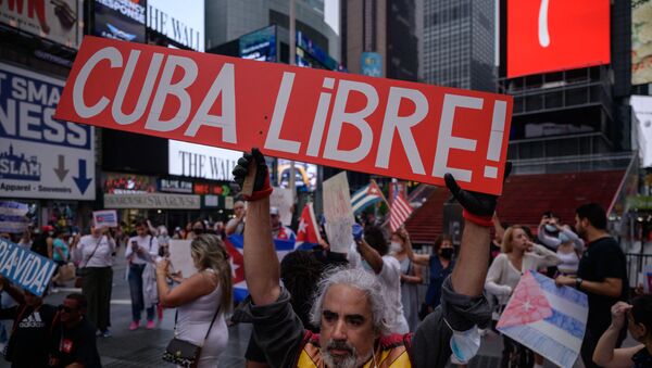 Demonstrators hold placards during a rally held in solidarity with anti-government protests in Cuba, in Times Square, New York on July 13, 2021. - One person died and more than 100 others, including independent journalists and dissidents, have been arrested after unprecedented anti-government protests in Cuba, with some remaining in custody on Tuesday, observers and activists said. - Sputnik International