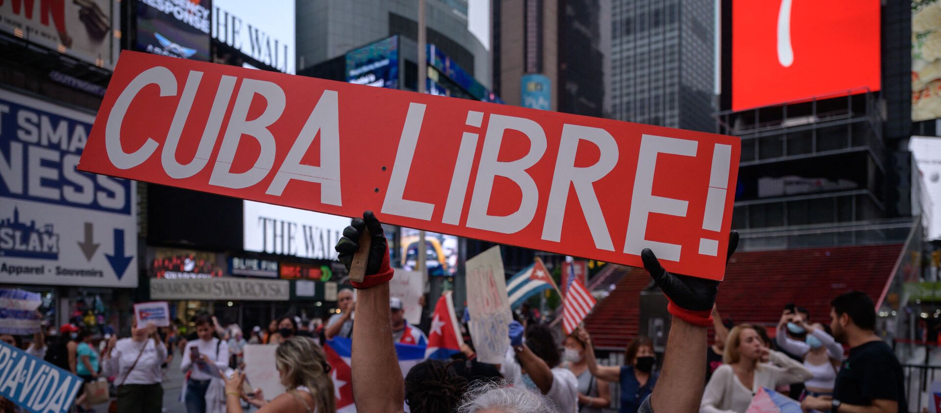 Demonstrators hold placards during a rally held in solidarity with anti-government protests in Cuba, in Times Square, New York on July 13, 2021. - One person died and more than 100 others, including independent journalists and dissidents, have been arrested after unprecedented anti-government protests in Cuba, with some remaining in custody on Tuesday, observers and activists said. - Sputnik International, 1920, 14.07.2021