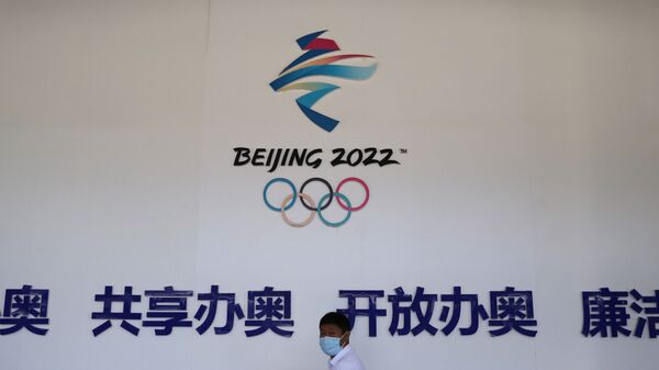 A man walks past a board with a sign of Beijing 2022 Winter Olympic Games at an exhibition hall during an organised media tour to venues of the Games in Zhangjiakou, Hebei province, China July 14, 2021 - Sputnik International