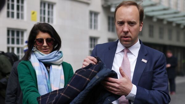 Britain's Health Secretary Matt Hancock hands his coat to his aide Gina Coladangelo (L) before a television interview outside BBC's Broadcasting House in London, Britain, May 16, 2021. Picture taken May 16, 2021 - Sputnik International