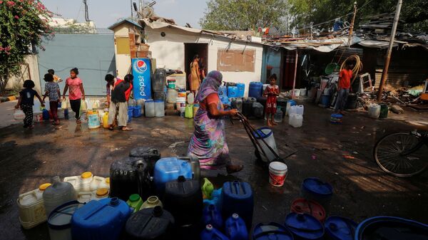 Residents carry containers after filling them with drinking water from a municipal tanker on a hot summer day in New Delhi, India, on 6 July 2021. - Sputnik International