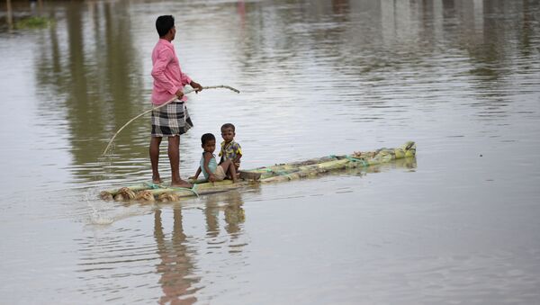 An Indian flood affected man rows a makeshift banana raft with two children in Gagolmari village, Morigaon district, Assam, India, Tuesday, July 14, 2020 - Sputnik International