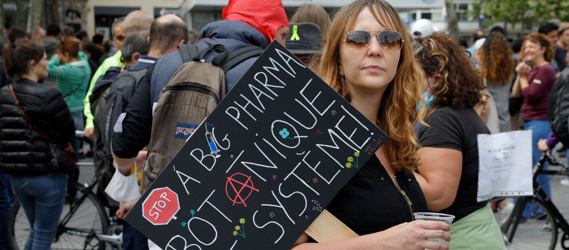 A woman holds a placard hostile to Pharmaceutical firms as she takes part in a gathering at Republic square in Paris on July 14, 2021 to protest against a governmental decision to impose Covid-19 tests for unvaccinated people who want to eat in restaurants or take long-distance trips, as the country looks to avoid a surge in more contagious Delta cases.  - Sputnik International, 1920, 17.07.2021