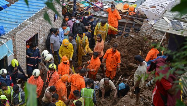 National Disaster Response Force (NDRF) and other rescue team personnel inspect the site of the landslide in a slum area where 18 people were killed after several homes were crushed by a collapsed wall and a landslide triggered by heavy monsoon rains in Mumbai on 18 July 2021. - Sputnik International