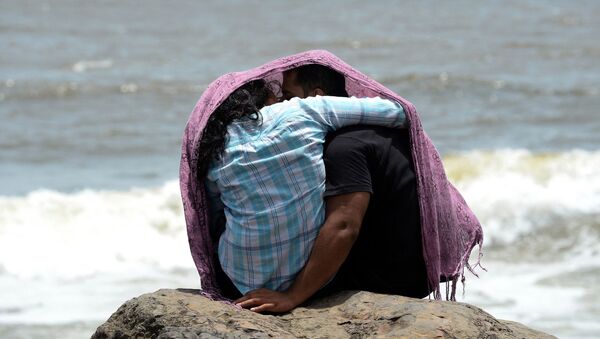 A young couple sit together on a rocky outcrop off the Arabian sea in Mumbai on July 3, 2015 - Sputnik International