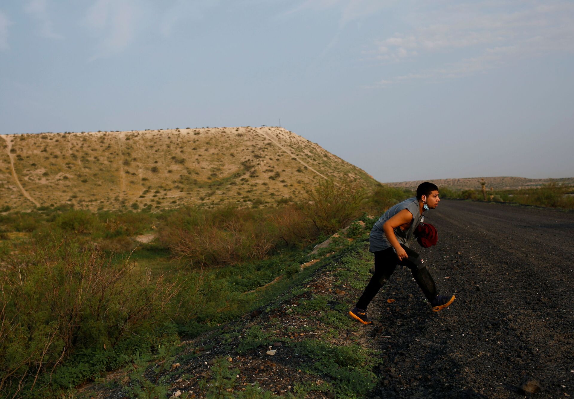 A migrant from Guatemala runs to hide from U.S. Border Patrol after crossing into the United States from Mexico, in Sunland Park, New Mexico, U.S., July 22, 2021 - Sputnik International, 1920, 07.09.2021