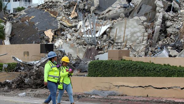 Rescue workers walk past debris after the managed demolition of the remaining part of Champlain Towers South complex as search-and-rescue efforts continue in Surfside, Florida, 6 July 2021. - Sputnik International