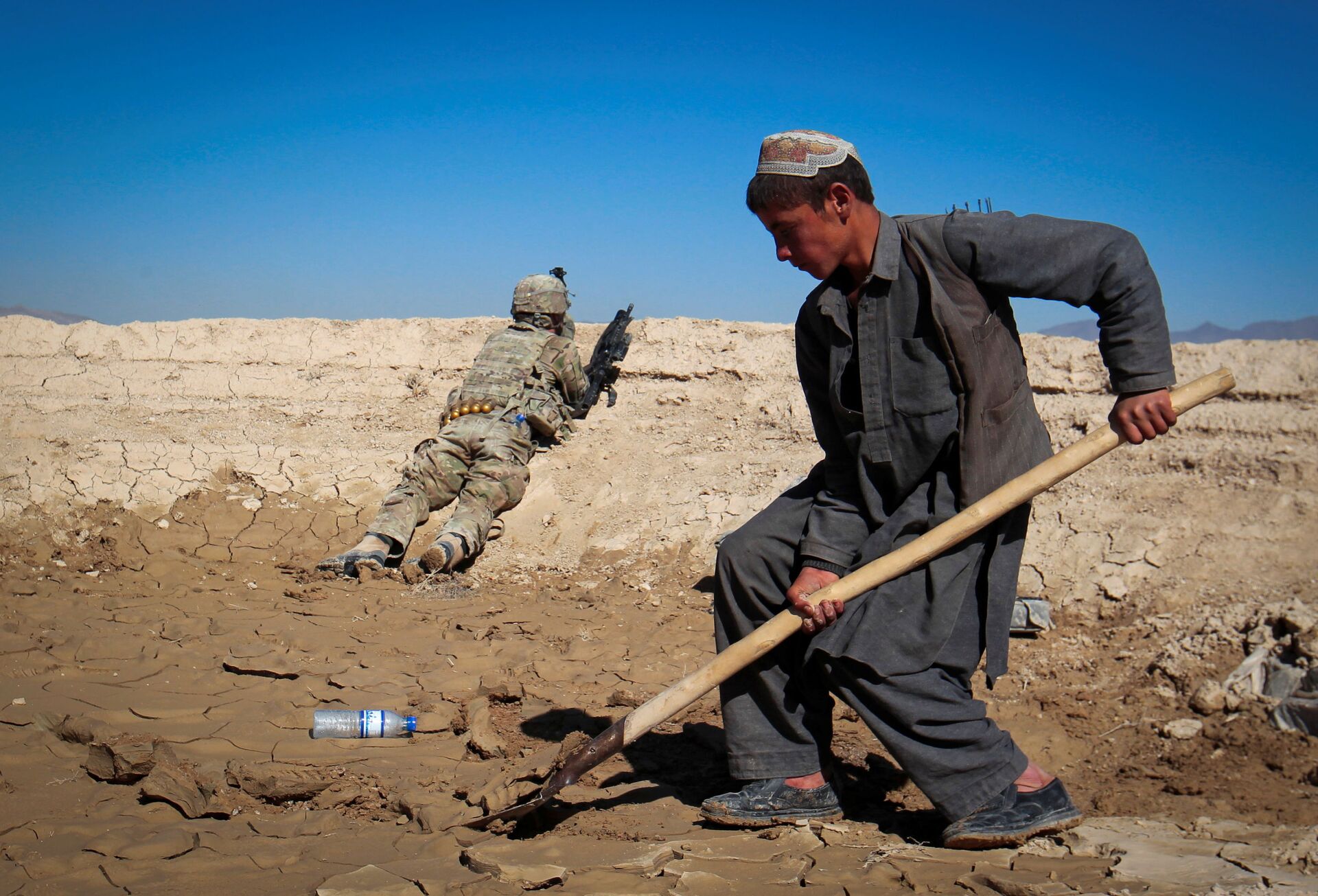 An Afghan boy works at a construction site as a U.S. Army soldier of 3/1 AD Task Force Bulldog takes position during a joint patrol with Afghan National Army (ANA) in a village in Kherwar district in Logar province, eastern Afghanistan, May 23, 2012.  - Sputnik International, 1920, 07.09.2021