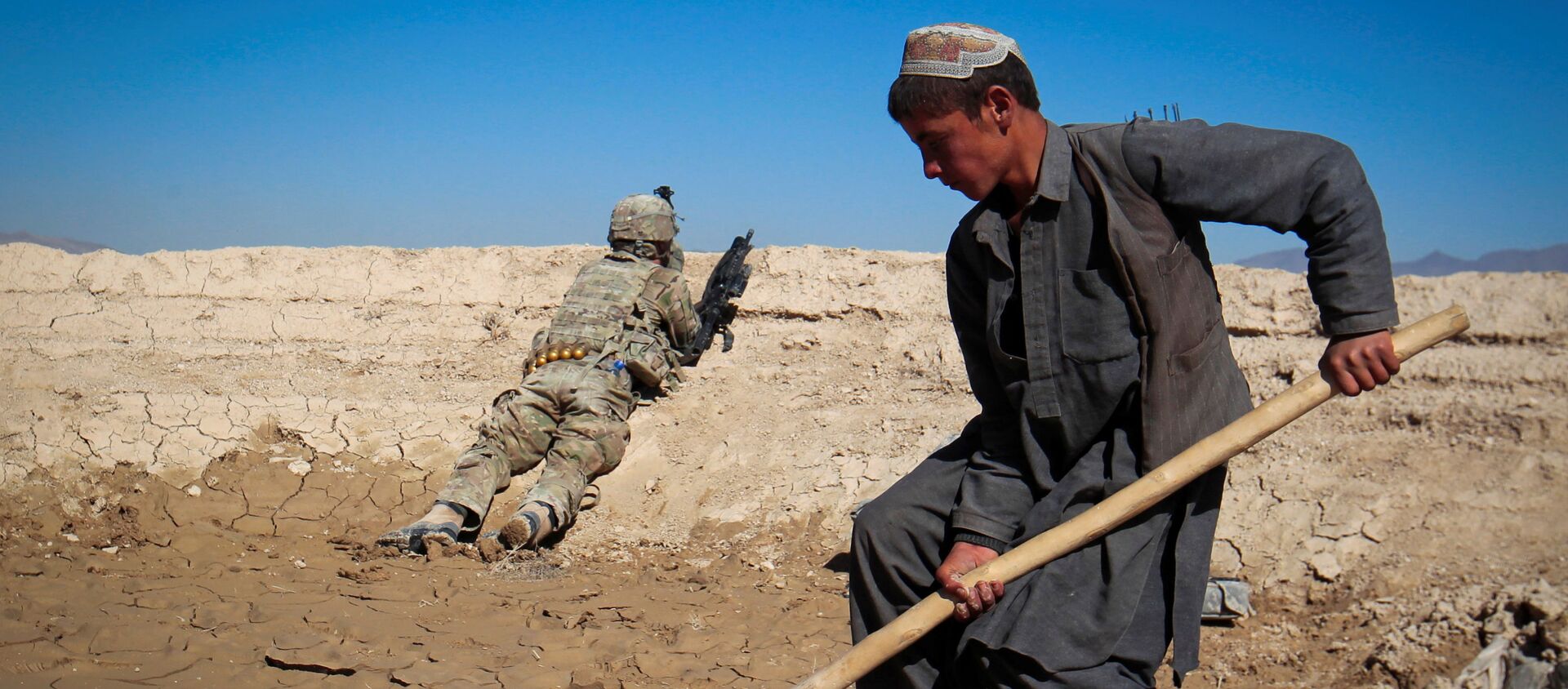 An Afghan boy works at a construction site as a U.S. Army soldier of 3/1 AD Task Force Bulldog takes position during a joint patrol with Afghan National Army (ANA) in a village in Kherwar district in Logar province, eastern Afghanistan, May 23, 2012.  - Sputnik International, 1920, 31.08.2021