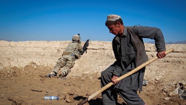An Afghan boy works at a construction site as a U.S. Army soldier of 3/1 AD Task Force Bulldog takes position during a joint patrol with Afghan National Army (ANA) in a village in Kherwar district in Logar province, eastern Afghanistan, May 23, 2012.  - Sputnik International