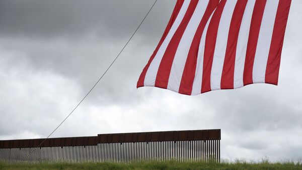 A flag flies in front of a section of the border wall ahead of a visit from former U.S. President Donald Trump and Texas Governor Greg Abbott along the U.S.-Mexico border in Pharr, Texas, 30 June 2021.  - Sputnik International