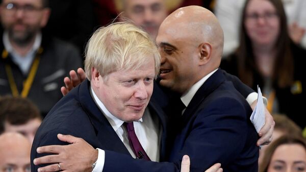 Britain's Prime Minister Boris Johnson is embraced by Britain's Chancellor of the Exchequer Sajid Javid before speaking to the workers as he visits a JCB factory during his general election campaign in Uttoxeter, Britain, December 10, 2019 - Sputnik International
