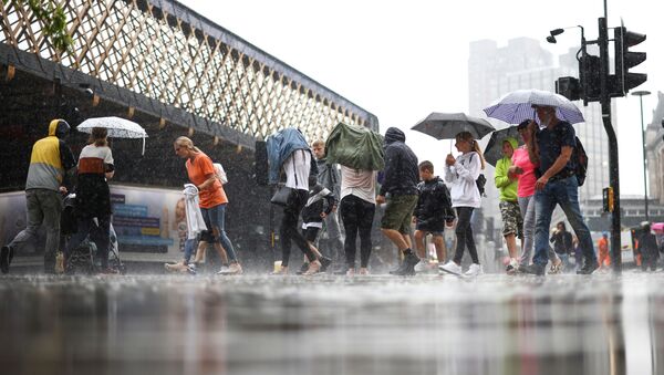 People walk through heavy rainfall, amid the coronavirus disease (COVID-19) outbreak, in London, Britain, July 25, 2021. - Sputnik International