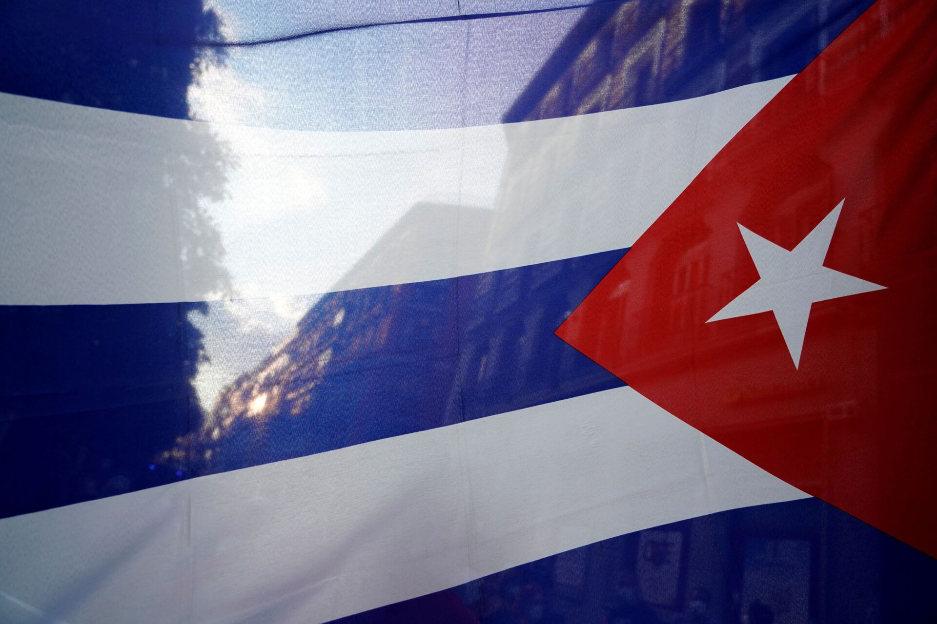 The silhouette of the city is seen through a Cuban flag during a protest against the  U.S. economic embargo in Cuba - Sputnik International, 1920, 07.09.2021