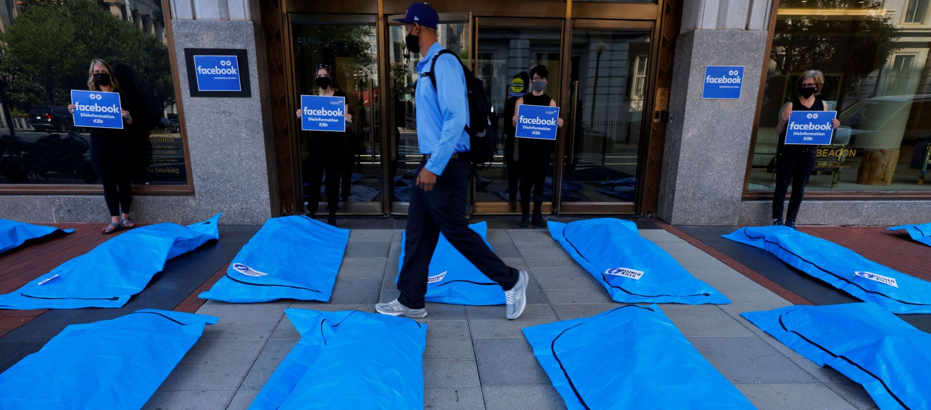 A pedestrian walks through an art installation of body bags as demonstrators protest against Facebook and what they claim is disinformation regarding coronavirus disease (COVID-19) on the social media giant's platform, outside Facebook headquarters in Washington, U.S., July 28, 2021 - Sputnik International, 1920, 29.07.2021