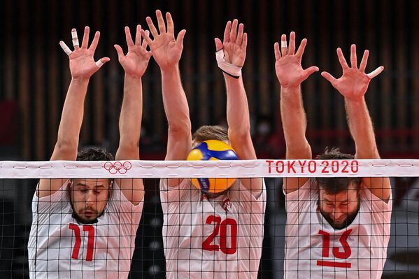 Poland's Fabian Drzyzga, Mateusz Bieniek, and Michal Kubiak attempt to block a shot in the men's preliminary round pool A volleyball match between Poland and Venezuela during the Tokyo 2020 Olympic Games at Ariake Arena. - Sputnik International