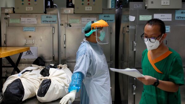 Health care workers stand near dead bodies prior moving them to a container, after a hospital morgue overwhelmed by COVID-19 deaths begun to store bodies in refrigerated containers, as the country struggles to deal with its biggest outbreak to date, in Pathum Thani, Thailand July 31, 2021 - Sputnik International