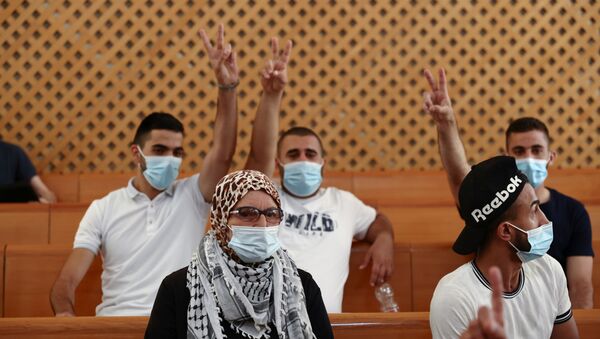 A supporter of the El-Kurd family, Palestinian residents of Sheikh Jarrah neighbourhood in East Jerusalem who are facing eviction, looks on as family members flash victory signs during a court hearing, in the Israeli Supreme Court, in Jerusalem August 2, 2021. - Sputnik International