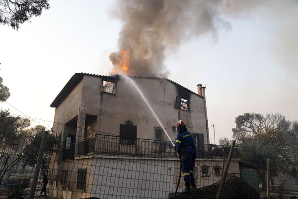 A firefighter tries to extinguish the flames at a burning house in the Varibobi area, northern Athens, Greece, Wednesday, 4 August 2021.  - Sputnik International