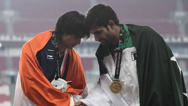 Gold medallist India's Neeraj Chopra (L) shakes hands with bronze medallist Pakistan's Arshad Nadeem during the victory ceremony for the men's javelin throw athletics event during the 2018 Asian Games in Jakarta on August 27, 2018.  - Sputnik International