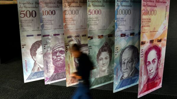 A man walks past banners showing banners depicting Venezuela's currency, the Bolivar, at the Central Bank of Venezuela (BCV) in Caracas on January 31, 2018.  - Sputnik International
