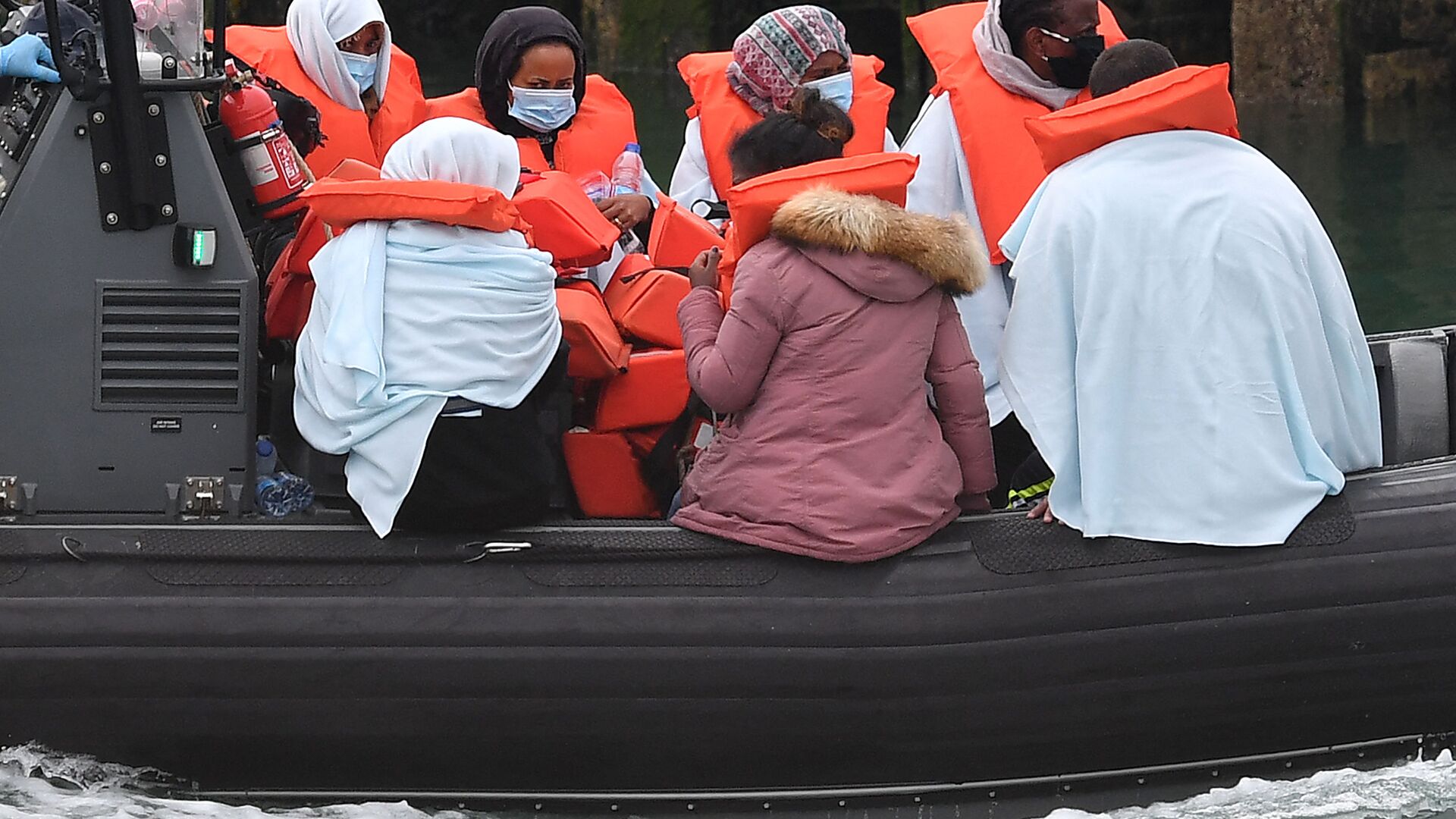 Migrants picked up at sea whilst Crossing the English Channel, but intercepted but intercepted bu UK Border Force officials, travel in a RIB with as they are brought into the Marina in Dover, southeast England on August 15, 2020. (Photo by Ben STANSALL / AFP) - Sputnik International, 1920, 18.11.2021