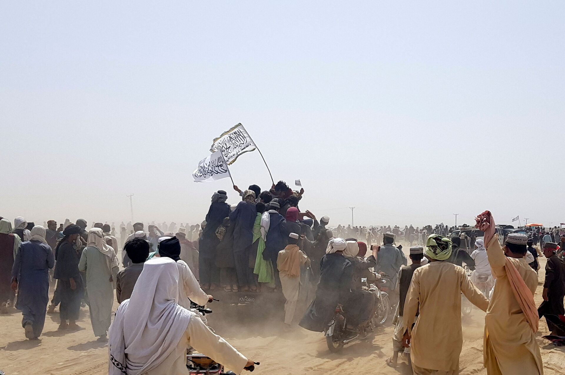 People standing on a vehicle hold Taliban flags as people gather near the Friendship Gate crossing point in the Pakistan-Afghanistan border town of Chaman, Pakistan July 14, 2021. Picture taken July 14, 2021. - Sputnik International, 1920, 07.09.2021