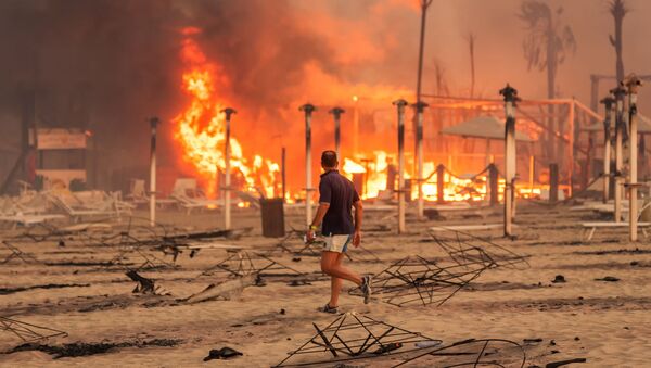 A man walks in front of a fire at Le Capannine beach in Catania, Sicily, Italy, July 30, 2021, in this photo obtained from social media on July 31, 2021 - Sputnik International