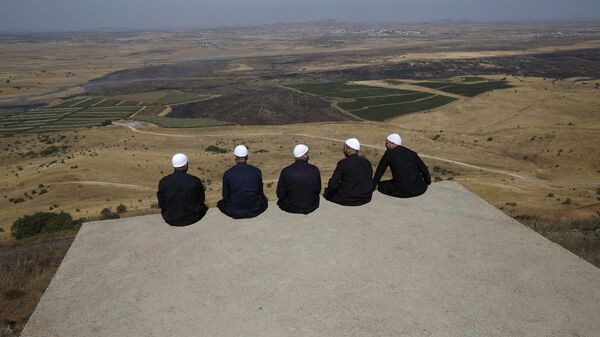 Druze men at the Israeli-annexed Golan Heights look out across the southwestern Syrian province of Quneitra, visible across the border on July 7, 2018  - Sputnik International