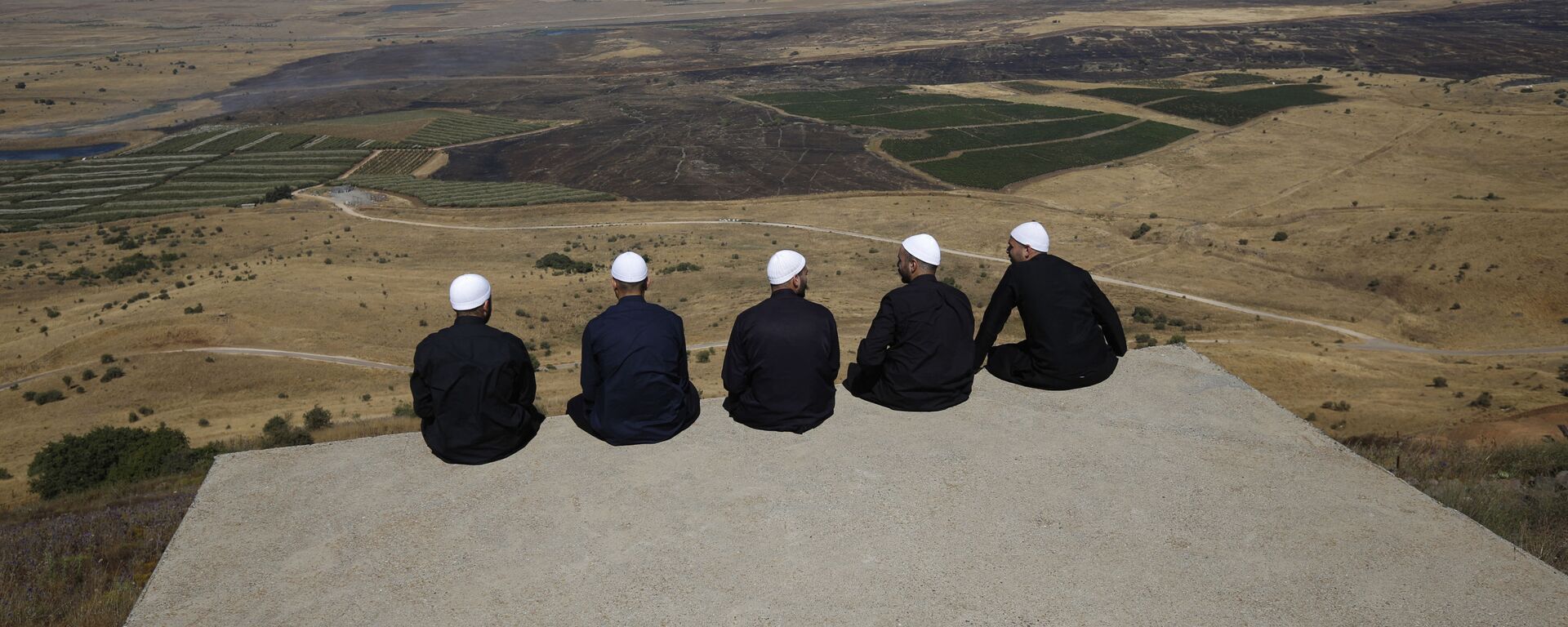 Druze men at the Israeli-annexed Golan Heights look out across the southwestern Syrian province of Quneitra, visible across the border on July 7, 2018  - Sputnik International, 1920, 09.09.2021