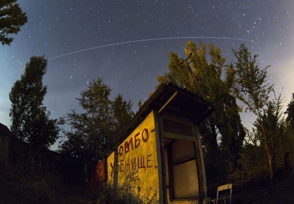 In this long-exposure photo, taken with a fisheye lens, the International Space Station (ISS) follows its orbit above an entrance with Bomb Shelter written on the side, where people hide from night shelling, in the Petrovsky district,  Donetsk, eastern Ukraine, on 4 August 2014. - Sputnik International