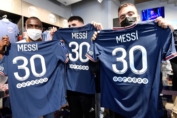 Supporters pose with jerseys of PSG's newest member, Argentinian football player Lionel Messi, that they have just bought at the Paris-Saint-Germain (PSG) football club store on the Champs Elysees in Paris on 11 August 2021. - Sputnik International