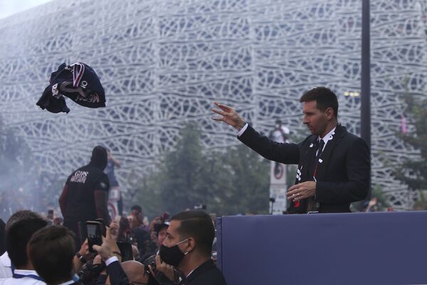 Lionel Messi throws a team jersey to Paris Saint-Germain supporters Wednesday, 11 August 2021 outside the Parc des Princes stadium in Paris.  - Sputnik International