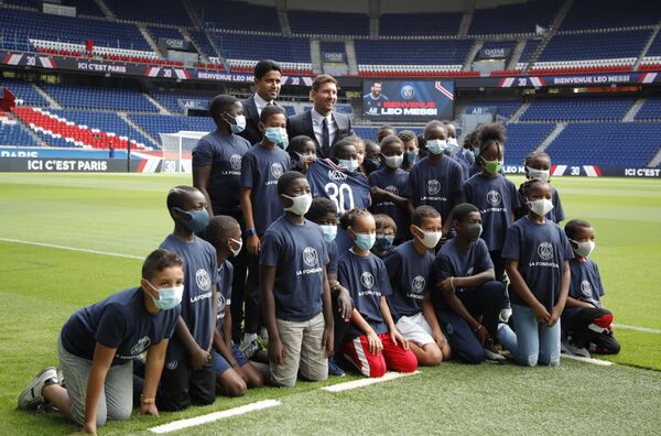 Paris St Germain's Lionel Messi and president Nasser Al-Khelaifi pose with children on the pitch after the press conference. - Sputnik International