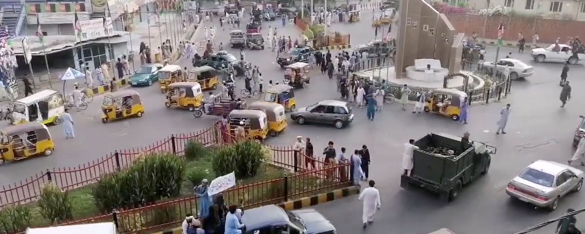 Taliban militants waving a Taliban flag on the back of a pickup truck drive past a crowded street at Pashtunistan Square area in Jalalabad, Afghanistan in this still image taken from social media video uploaded on August 15, 2021. Social media website/via REUTERS THIS IMAGE HAS BEEN SUPPLIED BY A THIRD PARTY. - Sputnik International, 1920