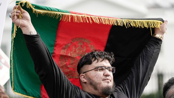A man holds Afghanistan's flag, as demonstrators shout Peace in Afghanistan and hold up signs as they gather in front of the White House in Washington, U.S., August 15, 2021 on the day Taliban insurgents entered Afghanistan's capital Kabul.   - Sputnik International