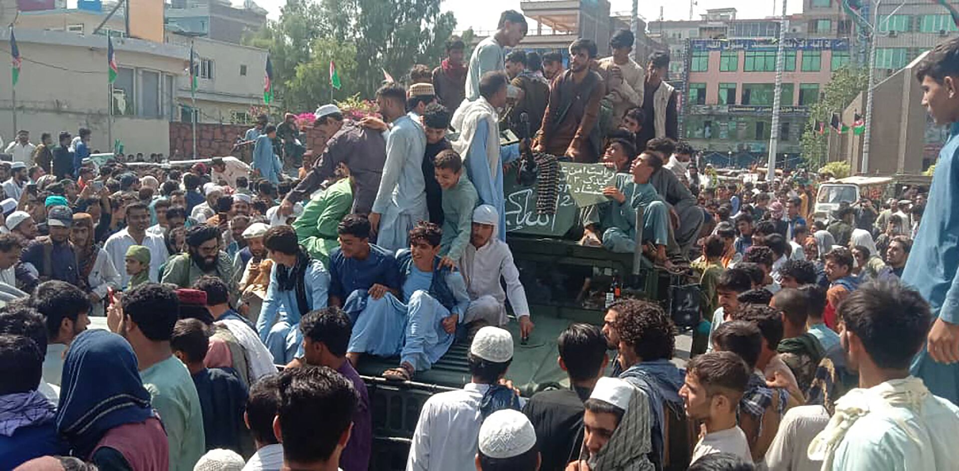 Taliban fighters and local people sit on an Afghan National Army (ANA) Humvee vehicle on a street in Jalalabad province on August 15, 2021.  - Sputnik International, 1920, 07.09.2021